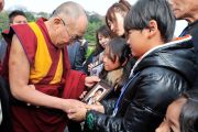 Местные жители показывают Его Святейшеству Далай-ламе фотографии близких, погибших во время разрушительного цунами в марте этого года. Исиномаки, Япония. 5 нояря 2011. Фото: Кимимаса Маяма