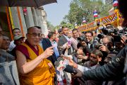 Его Святейшество Далай-лама приветствует толпу людей, встречающую его у тибетского монастыря в Бодхгае, Индия. 31 декабря 2011. Фото: Тензин Чойджор (офис ЕСДЛ)