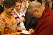 Его Святейшество Далай-лама подписывает свою книгу для одной из слушательниц после лекции на стадионе "Лэйкфрант Арена" в Новоорлеанском университете. Новый Орлеан, штат Луизиана, США. 18 мая 2013 г. Фото: Джереми Рассел (офис ЕСДЛ)