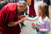 Его Святейшество Далай-лама здоровается с девочкой у входа в университет Эразма Роттердамского. Роттердам, Голландия. 12 мая 2014 г. Фото: Jurjen Donkers