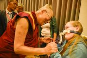 Его Святейшество Далай-лама здоровается с одной из слушательниц в инвалидном кресле перед началом послеполуденной лекции в гамбургском конгресс-холле. Гамбург, Германия. 23 августа 2014 г. Фото: Мануэль Бауэр