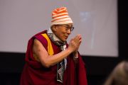 По завершении лекции Его Святейшество Далай-лама в подаренных ему студентами норвежских шарфе и шапочке благодарит участников международного студенческого фестиваля в Тронхейме.