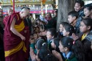 Его Святейшество Далай-лама приветствует тибетских школьников, покидая главный тибетский храм после учений по Джатакам. Дхарамсала, Индия. 5 марта 2015 г. Фото: Тензин Чойджор (офис ЕСДЛ)