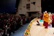 Его Святейшество Далай-лама приветствует аудиторию в начале второй сессии первого дня учений в университете Шова. Токио, Япония. 12 апреля 2015 г. Фото: Тензин Джигме