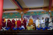 Его Святейшество Далай-лама и почетные гости стоя слушают гимны Индии и Тибета на официальной церемонии в честь 26-й годовщины вручения Его Святейшеству Нобелевской премии мира. Хунсур, штат Карнатака, Индия. 10 декабря 2015 г. Фото: Тензин Чойджор (офис ЕСДЛ)