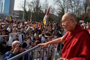 Его Святейшество Далай-лама приветствует трехтысячную толпу тибетцев и сторонников Тибета, собравшуюся на площади перед Дворцом Наций в Женеве. Женева, Швейцария. 11 марта 2016 г. Фото: Оливье Адам