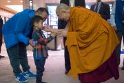 Его Святейшество Далай-лама здоровается с маленьким мальчиков по дороге в зал, где будут проходить учения. Осака, Япония. 10 мая 2016 г. Фото: Тензин Чойджор (офис ЕСДЛ)